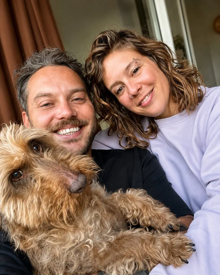 Alex en Malu zitten naast elkaar met hun hond Broes op schoot